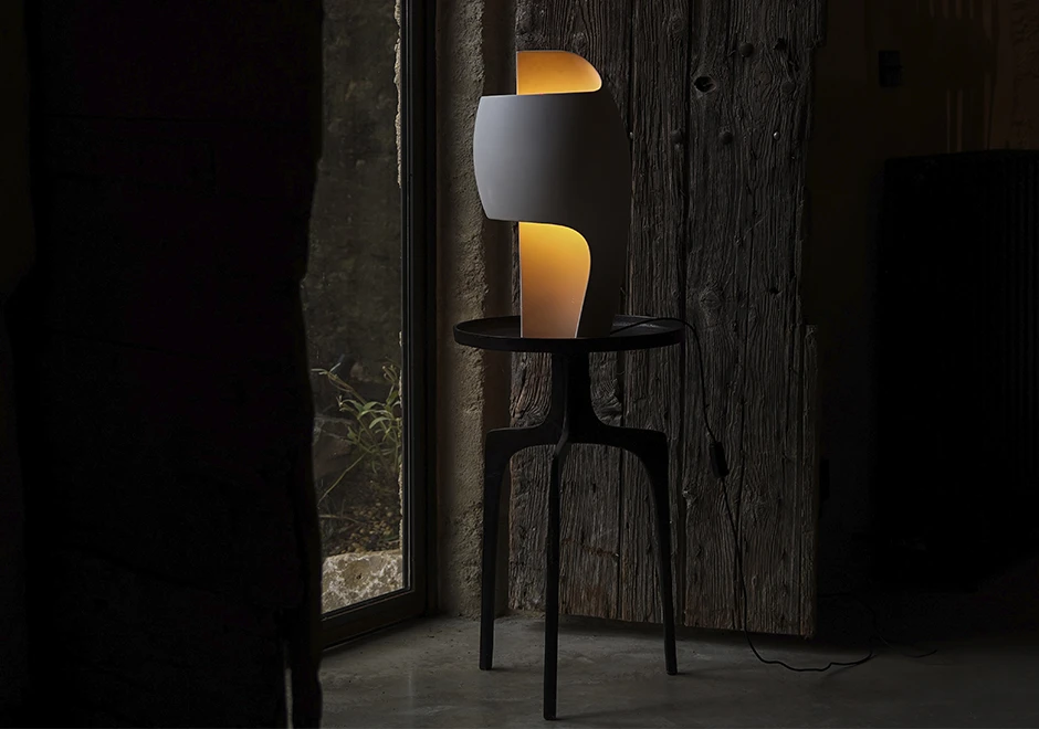 Luminária Lampe B preta, iluminando ambiente escuro.