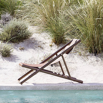 Vista lateral da cadeira Clever Foldable da marca Varaschin, na praia.